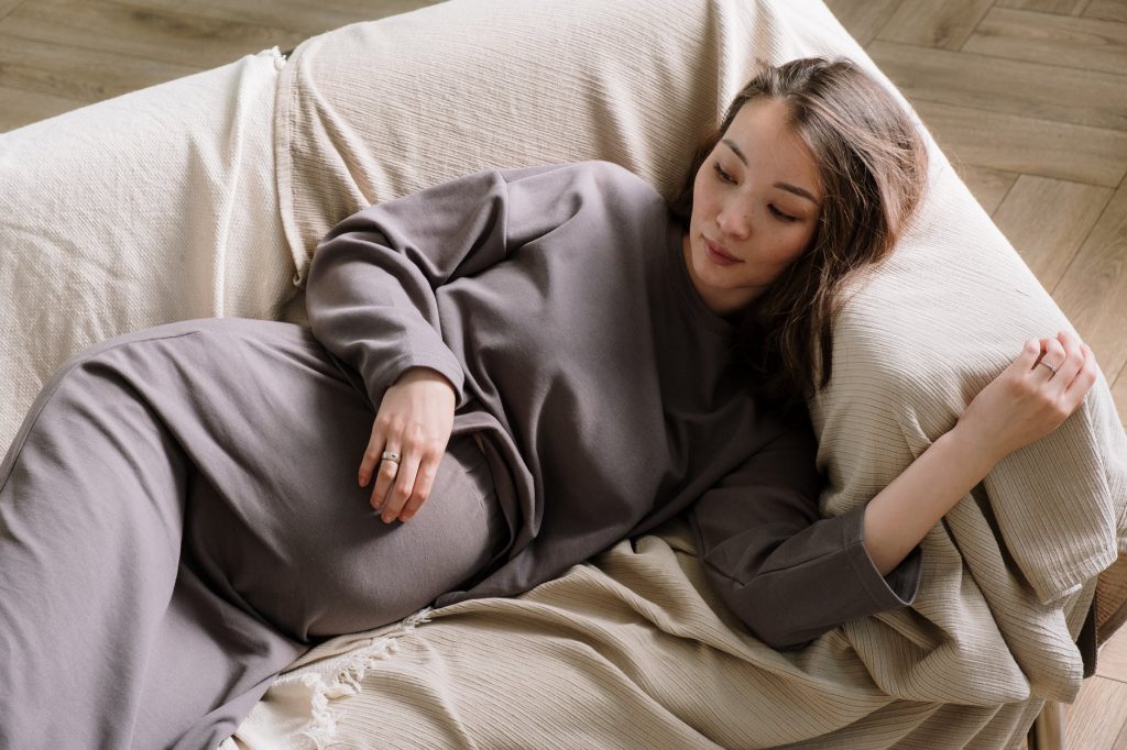 woman in gray long sleeve shirt lying on bed