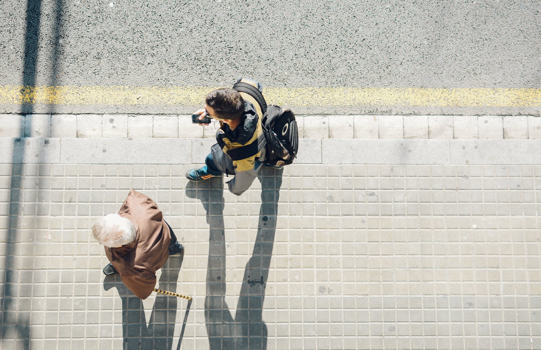 high angle photography of two person walking beside road